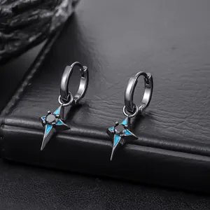 Close-up of black four-pointed star pendant earrings with blue accents on textured background