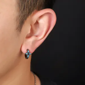 Close-up detail of a stylish four-pointed star zircon stud earring worn on a male ear