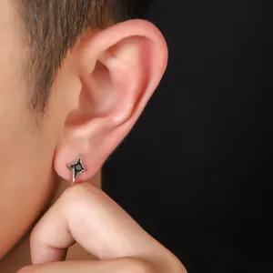 Macro view of a black zircon four-pointed star stud earring worn on a male ear