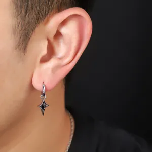 Detail of silver hoop earring with four-pointed star and black gemstone pendant