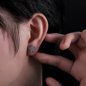 Gros plan détaillé d'une boucle d'oreille étoile en zircons scintillants sur un lobe.