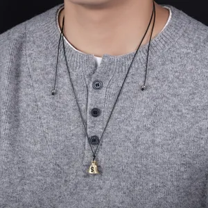 Detailed view of a golden money bag necklace pendant with dollar sign on black cord