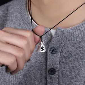Macro view of a silver money bag pendant necklace with a minimalist black cord