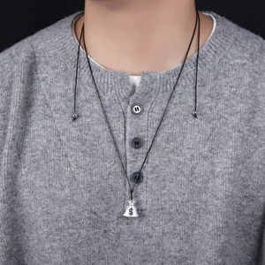 Close-up detail of a silver money bag pendant on a black cord necklace worn on a gray sweater