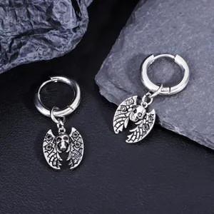 Close-up of gothic stainless steel bat skull earrings on stone texture background