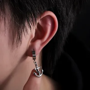 Detailed macro shot of a polished stainless steel anchor pendant earring worn on ear