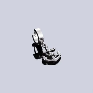 Close-up detail of a silver stainless steel anchor charm earring on a reflective surface