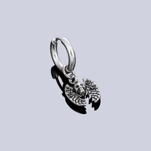 Detail of stainless steel hoop earring with vintage bat skull pendant charm