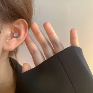 Detail view of a minimalist non-pierced crystal ear stud worn on a model's ear cartilage