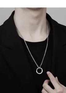 Collier pendentif anneau de Möbius argenté sur mannequin homme en blazer noir au style chic.