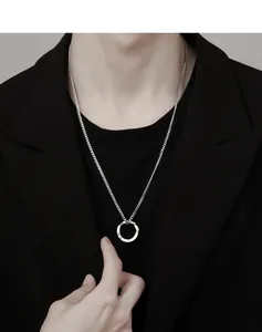 Vue détaillée d'un collier avec pendentif anneau Mobius argenté porté par un homme.