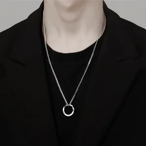 Collier pendentif anneau de Moebius en argent pour homme, porté sur un blazer noir élégant