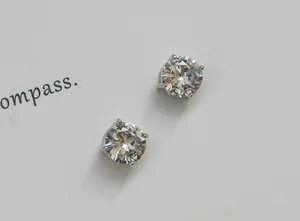 Detailed view of minimalist non-pierced stud earrings featuring clear faceted stones