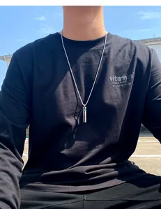 Close-up of men's titanium steel cylinder perfume bottle pendant on a black t-shirt