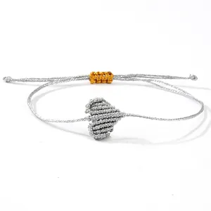 Bracciale a cuore in argento intrecciato a mano con nodo dorato su fondo bianco