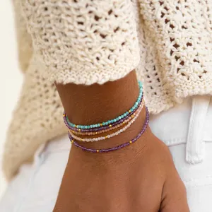Detailopname van boho kralenarmbanden met halfedelstenen gestapeld om een pols.
