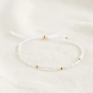 Detailopname van een boheemse kralenarmband met gouden kralen op een witte ondergrond