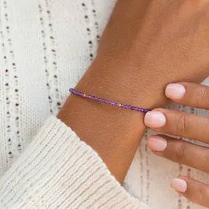 Close-up van een delicate paarse amethist kralenarmband om de pols van een vrouw