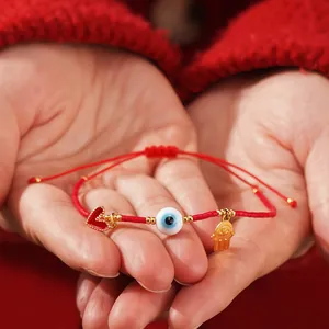 Red evil eye seed bead bracelet with heart and hamsa hand charms in cupped hands