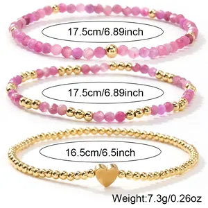 Juego de tres pulseras artesanales de cristal rosa y cuentas doradas con dije de corazón.