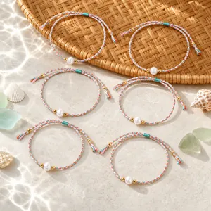 Macro detail of colorful braided bracelets with white pearls and gold metal accents