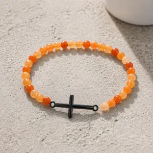 Vista detallada de las cuentas naranjas de 6mm y la cruz negra en pulsera