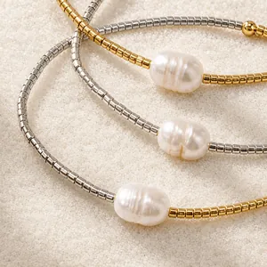 Minimalist mixed metal beaded bracelets with large white oval pearls on textured background