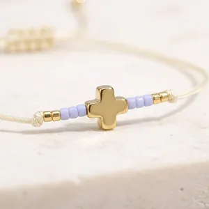 Delicate woven bracelet with a gold cross and soft lavender rice beads for women