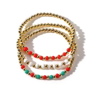 Set of three Christmas beaded bracelets with gold, red, green, and white festive charms