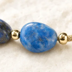 Gros plan d'un bracelet en pierre naturelle bleue avec perles dorées
