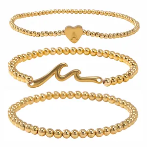 Ensemble de trois bracelets élastiques à billes dorées avec breloques cœur et vague