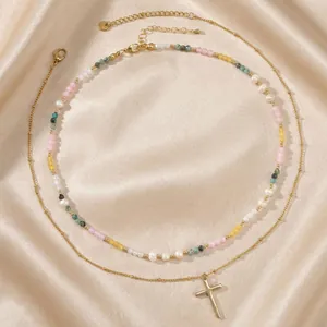 Elegant double-layered gold necklace with colorful beads, natural pearls and a cross pendant.
