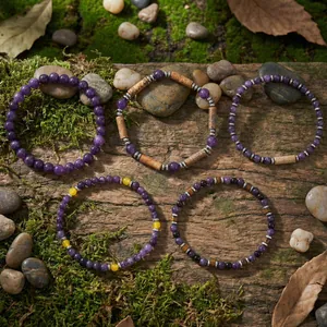 Set van vijf amethist en halfedelsteen kralenarmbanden op een bemost stukje hout.