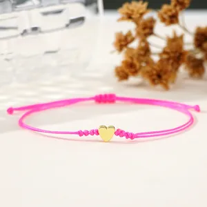Delicate pink braided cord bracelet featuring a minimalist gold heart charm pendant