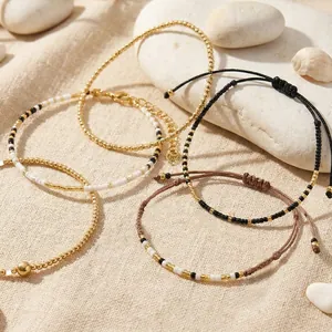 Set of handmade seed bead woven bracelets with gold beads and black-white contrast design