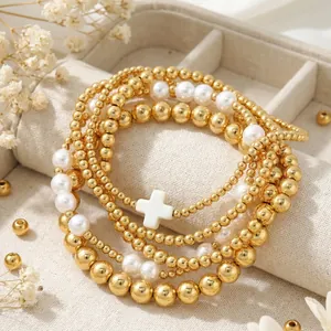 Elegant multi-layer gold beaded bracelet set featuring white pearls and a cross charm detail
