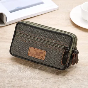 Close-up detail of a durable green canvas men's phone belt bag with three zipper compartments