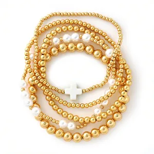 Elegant gold beaded bracelet set with white pearls and cross charm on white background