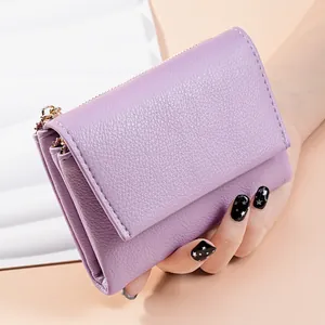 Close-up of purple pebbled leather trifold wallet held in hand showing detail