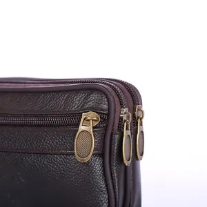 Close-up detail of premium brown synthetic leather waist bag with double antique brass zippers