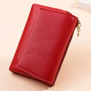 Macro view showing the red pebbled leather texture and gold heart zipper on this mini wallet