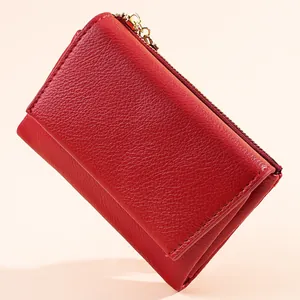 Close-up detail of a red pebbled leather mini wallet featuring a golden zipper closure