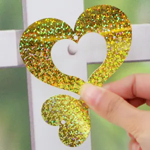 Close-up view of golden holographic heart-shaped PVC sequins with hanging holes