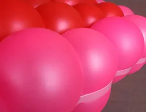 Macro detail of thick matte pink and red latex balloons in a decorative grid