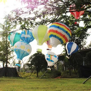 Bunte Heißluftballon-Papierlaternen, die dekorativ im Freien an Baumzweigen hängen