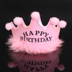 Detailed close-up view of a pink felt birthday crown hat with pom-poms and feathers