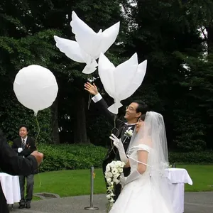 Palloncini a forma di colomba bianca liberati dagli sposi durante un matrimonio all'aperto.