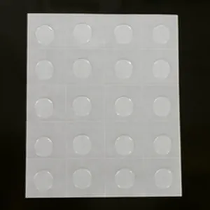 Detailed close-up of clear double-sided adhesive glue dots on white backing sheet
