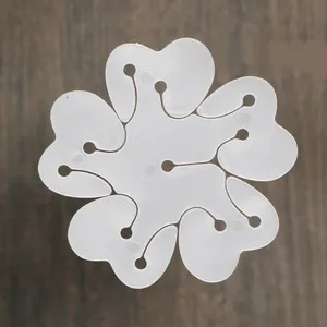 Vista detallada de un clip para globos de plástico blanco con forma de flor para fiestas.