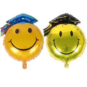 Detail of two smiley face foil balloons wearing blue and black graduation caps.